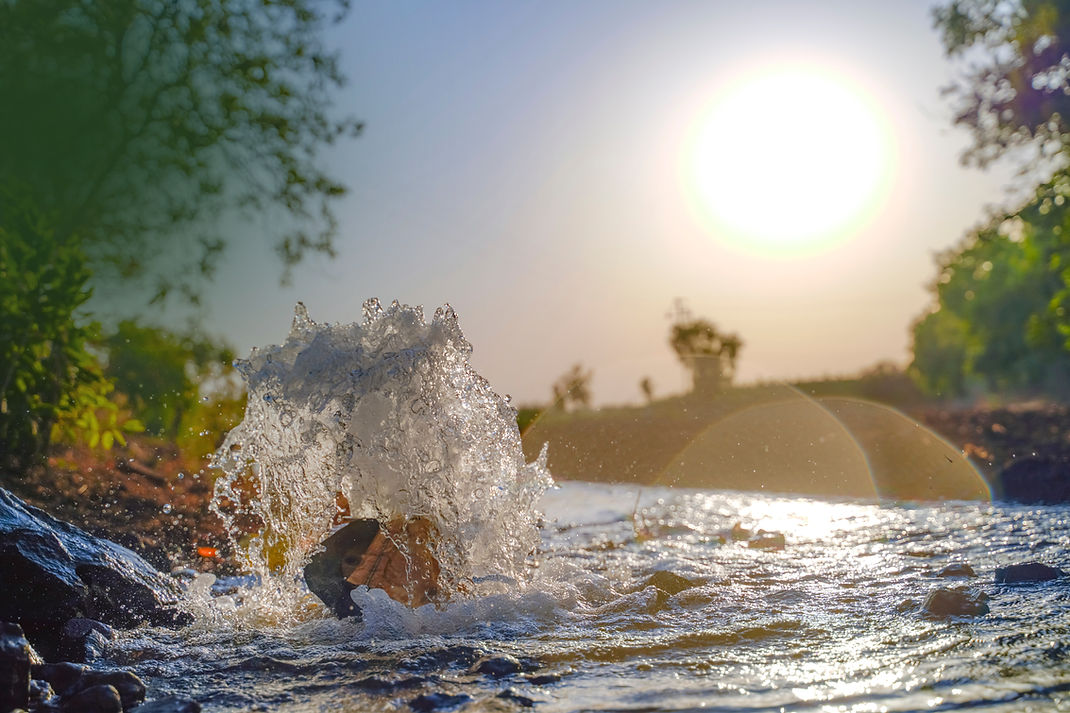 Water splashing in a sunlit stream at sunset.