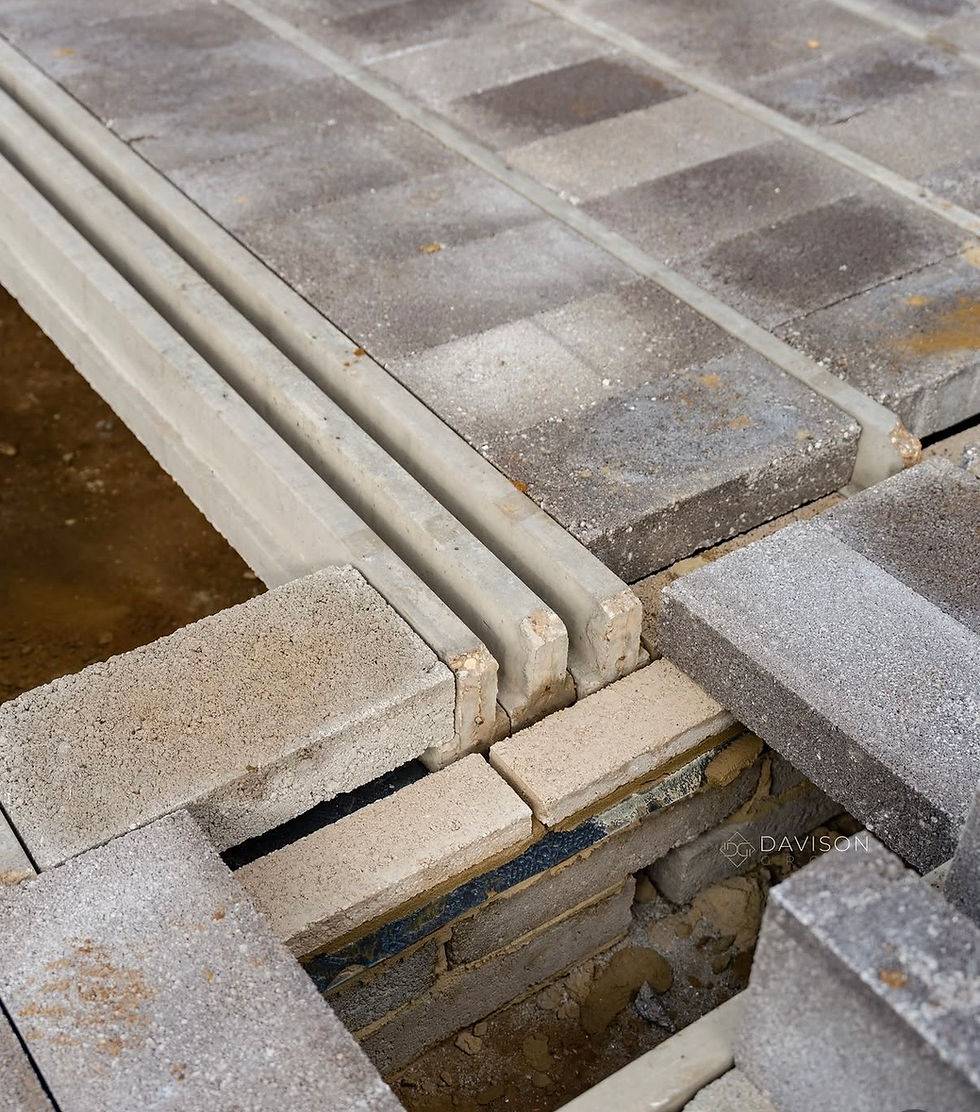 Close-up of gray concrete pavers and blocks over a gap, showing construction details and a DAVISON watermark.