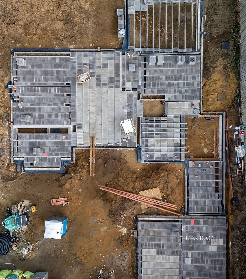 Aerial view of a house foundation under construction, with gray slab panels, dirt lots, scattered bricks and pipes, and DAVISON watermark.