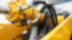 Custom hydraulic hose fittings installed on a heavy-duty cylinder in construction equipment.