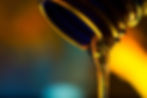 Close-up of golden hydraulic fluid being poured from a container under warm lighting.
