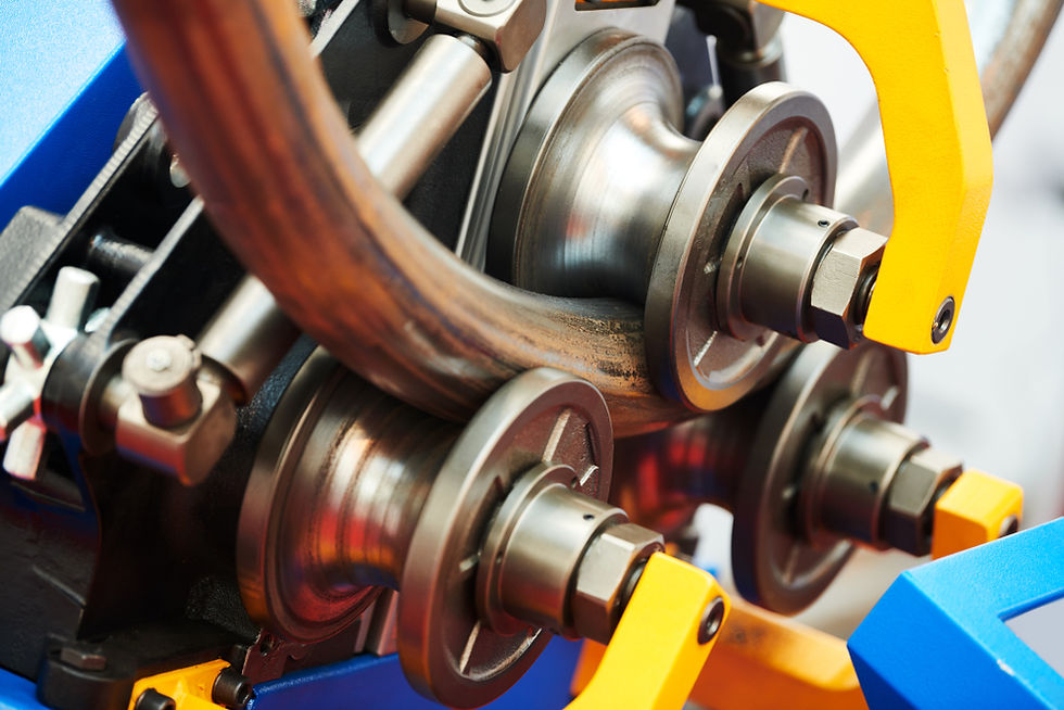 Close-up of a pipe roll bending machine, showing precision rollers shaping a metal pipe.