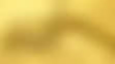Golden hydraulic oil being poured in slow motion, showing its clarity and viscosity on a yellow backdrop.