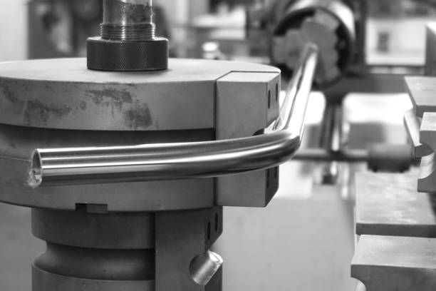 A close-up view of a hydraulic pipe bending machine forming a precise curve in a metal pipe.