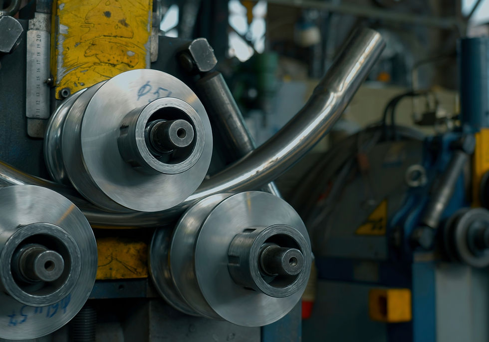 Hydraulic pipe bending machine shaping a curved metal pipe in a workshop.