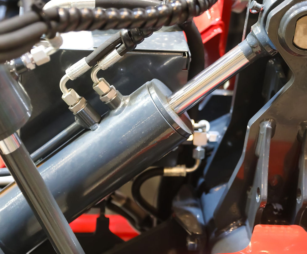 Close-up of a hydraulic cylinder in a machine, showing connecting hoses and fittings.