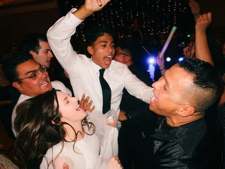 A lively group of wedding guests dancing and celebrating on a crowded dance floor. 