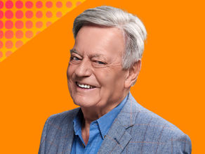 Radio presenter Tony Blackburn smiles against an orange background
