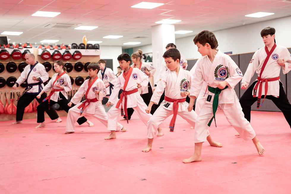 Kids in white Tang Soo Do uniforms practice martial arts stances on a pink mat in a dojo, focused and disciplined.
