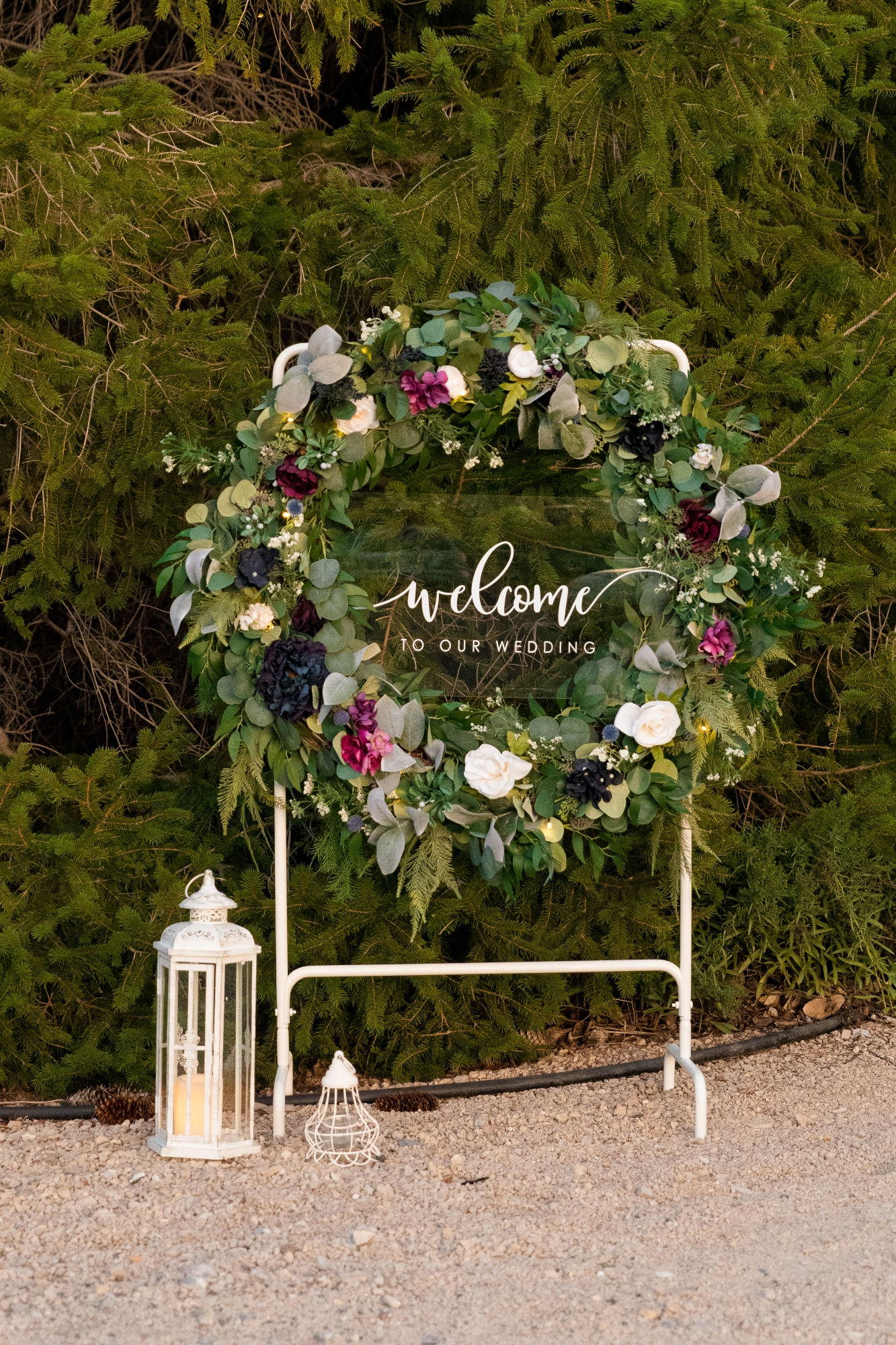 Large floral wreath on easel with “Welcome to our wedding” sign