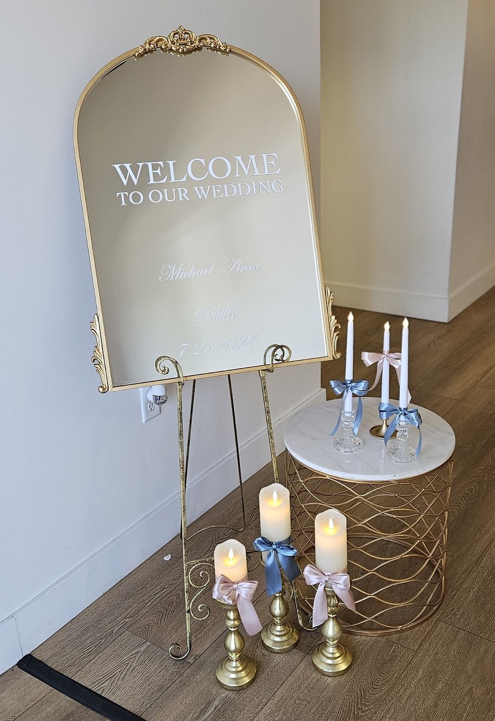 Gold mirror on easel with nearby candles and taper holders on a modern drum table.