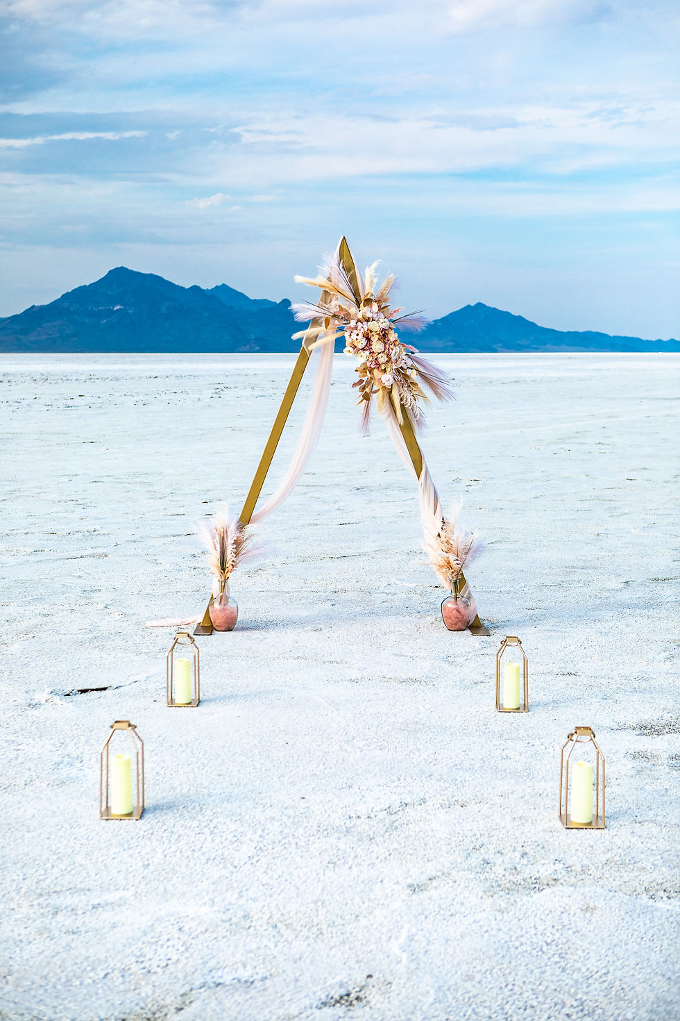 Gold A frame Arch with blush drape, blush and cream florals, and gold lanterns at the Utah Salt Flats with wedding rentals