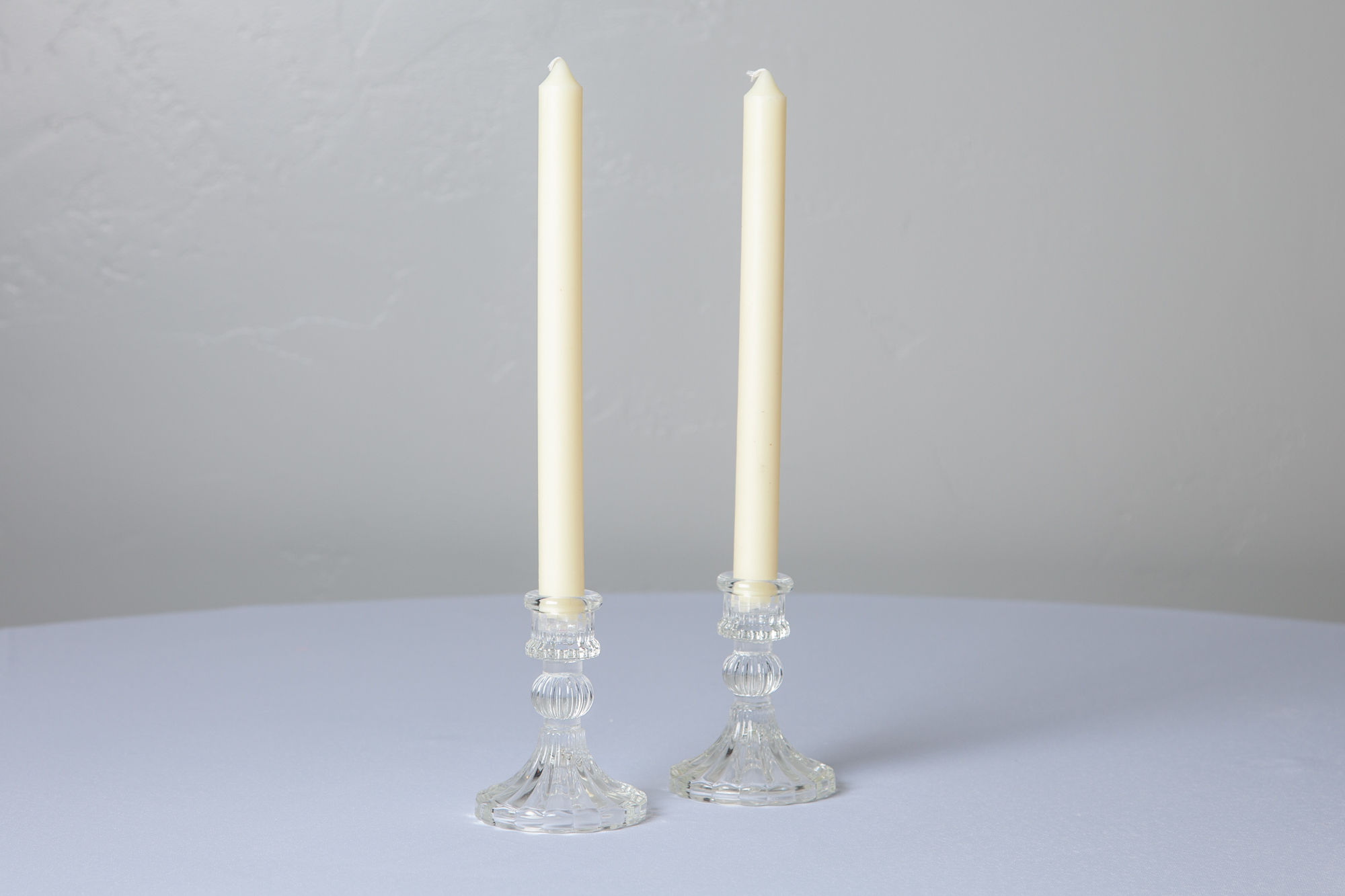 Ivory taper candles in clear holders on white tabletop