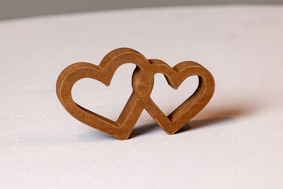 Wooden interlocking hearts decor on white linen backdrop, ideal for sweetheart table or rustic wedding accent.