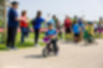 Volunteer in teal shirt directing youth participants at the bike transition area during an outdoor triathlon