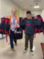 teacher and student holding donated backpacks