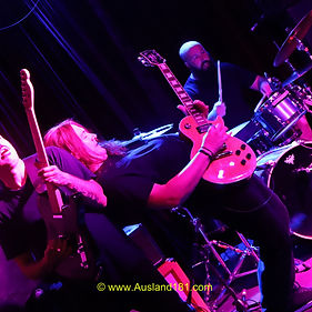 With the recent released #rockslab release, “Green Machine” setting a benchmark for driving, anthemic, guitar rock Electric State surprised all by featuring four new songs in their eleven song set. 
However being surprised at a Electric State gig is no surprise.
Back to the music, among the new compositions “Background Noise” stuck in my head. 
Meanwhile Rob was at his eccentric and oddball best. Off stage walk-abouts, random interviews with the music aficionado’s present, beard quality testing, matching their fifth member, Janice the Megaphone, with a consort for the evening, Mexican stand-off’s with local on-air Rock Legend Frankinator (yes, he and Ryan of Rockaria 107.3 HFM fame were present) for allegedly snuffing out the Frankinator’s beloved cap and all while conducting audience sing-alongs.
Of the current white-hot “Green Machine” release numbers, where all songs are stormers, “Fed by the Algorithm” is a personnel fav, while the Rockaria Heads vouch for “Run”. 
“Get In You”, “Light It Up”, F$#k My Head (FMH)”, “Mirror” and “Tomorrows Sun” were the remaining “Green Machine” items featured.
Maintaining their energy they are also heading into the studio in the forth coming weeks, capturing the energy and up-tempo vibrations for the next release. Riding the Wave Indeed! 
And lets not forget The Cowbell, spreading the love in the closing songs. 
Another riot in the basement, cleansing the space, and all captured in the Gig Photos – click the button below.
Rob- Guitar/Vocals/Megaphone, Russ-Riff Master Guitar, Paul-Rampaging Bass, Bill-Green Machine Drums