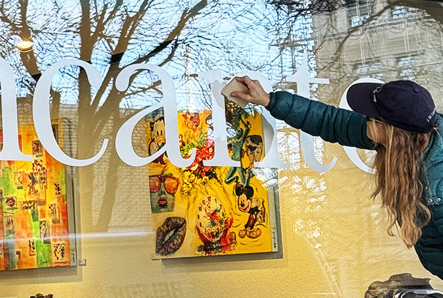 Person hängt beschriftet Schaufenster mit Schriftzug