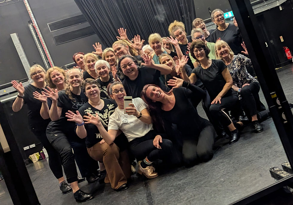 A group of dancers smiling and waving in a studio
