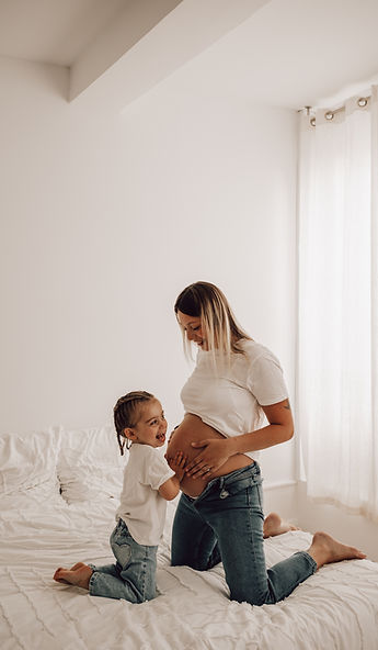Une femme enceinte faisant touché son ventre à sa petite fille