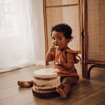 Photographie d'une petite fille assise au sol mangeant du gâteau