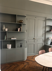 Bibliothèque murale sur mesure dans une salle à manger élégante. Cette bibliothèque intégrée et personnalisée est conçue sur mesure en médium à peindre, avec des étagères ouvertes et des rangements fermés. Elle s'intègre harmonieusement dans un espace de vie moderne, alliant fonctionnalité et esthétique. Idéale pour exposer des objets décoratifs et ranger des livres, cette pièce en médium offre un agencement élégant et sur mesure pour un intérieur raffiné.