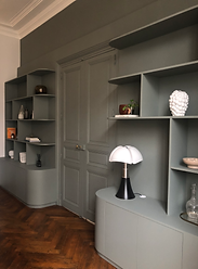 Bibliothèque murale sur mesure dans une salle à manger élégante. Cette bibliothèque intégrée et personnalisée est conçue sur mesure en médium à peindre, avec des étagères ouvertes et des rangements fermés. Elle s'intègre harmonieusement dans un espace de vie moderne, alliant fonctionnalité et esthétique. Idéale pour exposer des objets décoratifs et ranger des livres, cette pièce en médium offre un agencement élégant et sur mesure pour un intérieur raffiné.