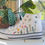 Thumbnail: White high-top canvas shoes with embroidered wildflowers, facing left.