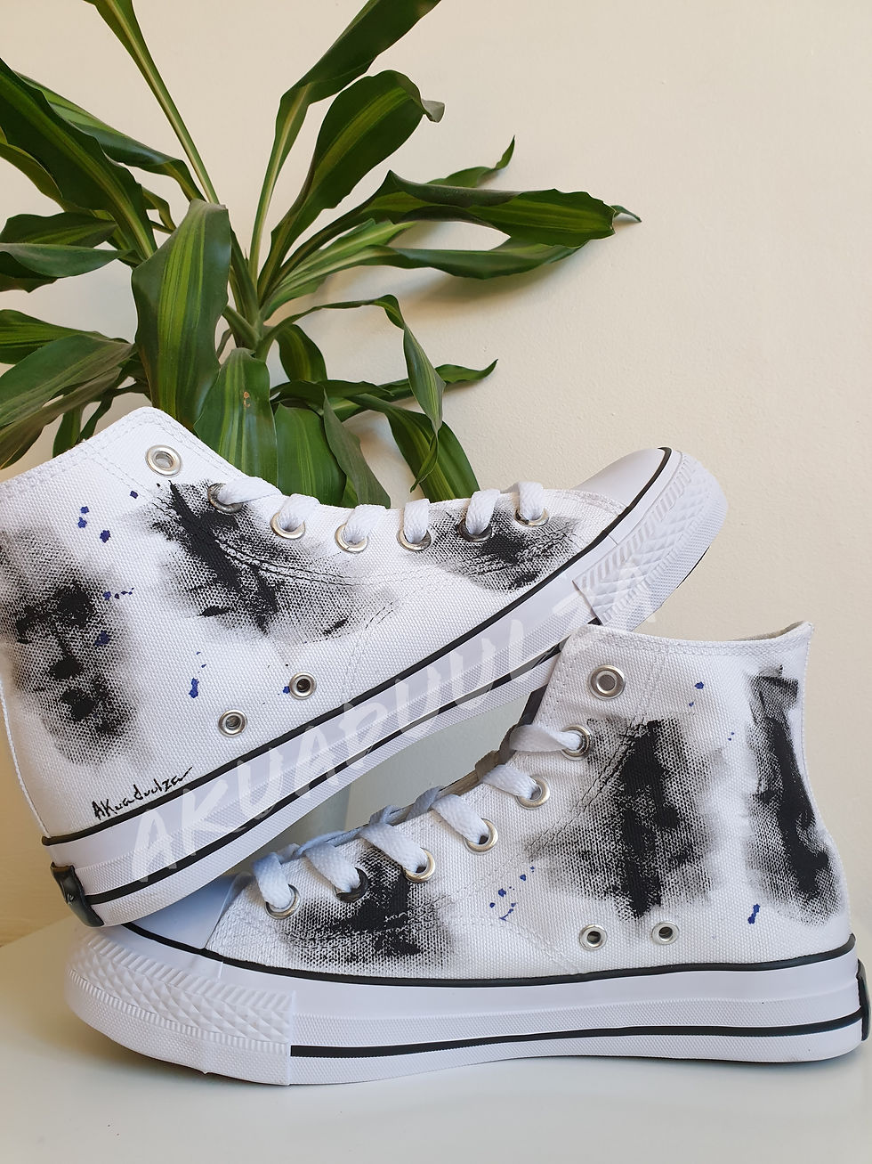 Black and white hand-painted abstract design on white high-top shoes.