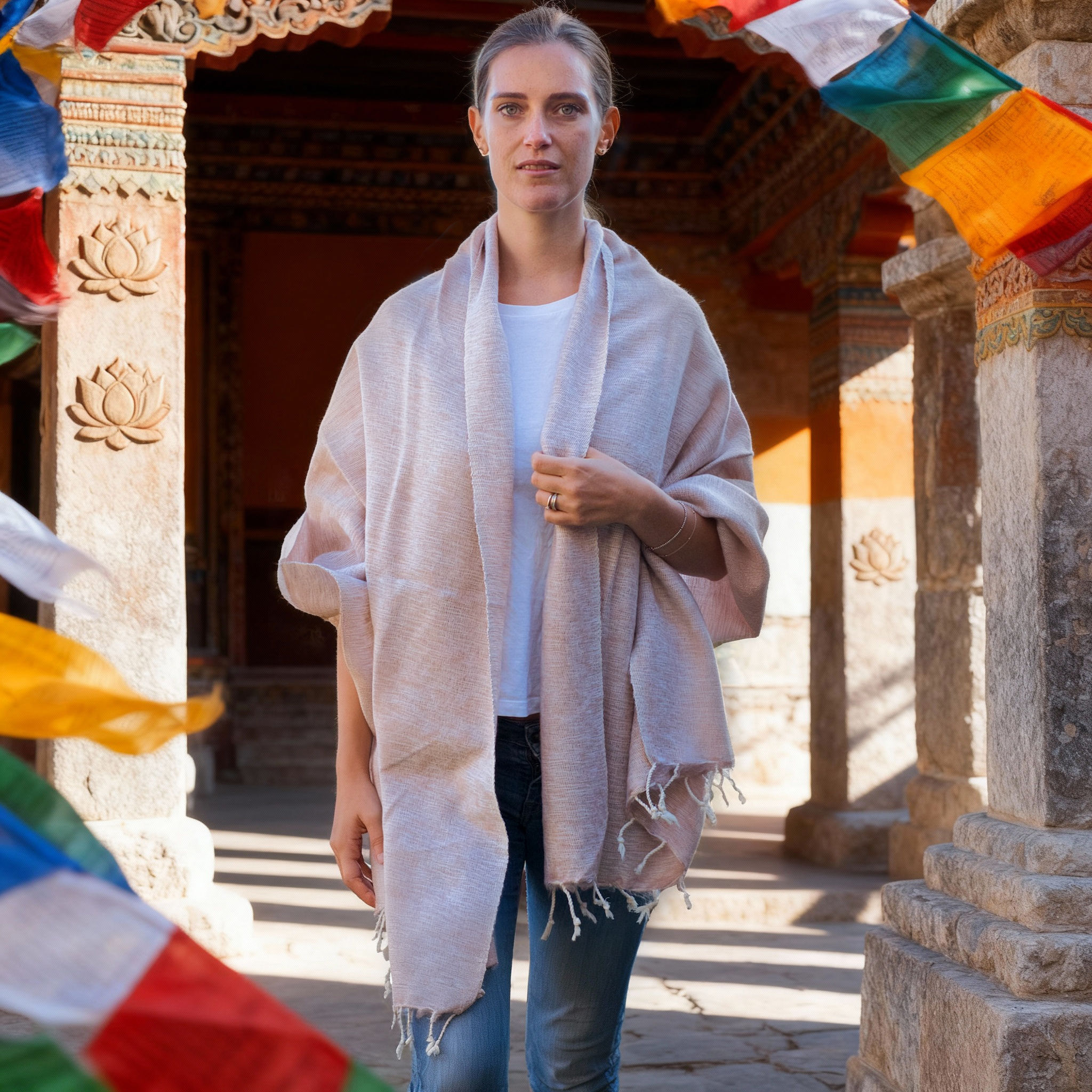 Donna, che guarda avanti, indossa uno scialle in lana yak color crema in cortile con bandiere.