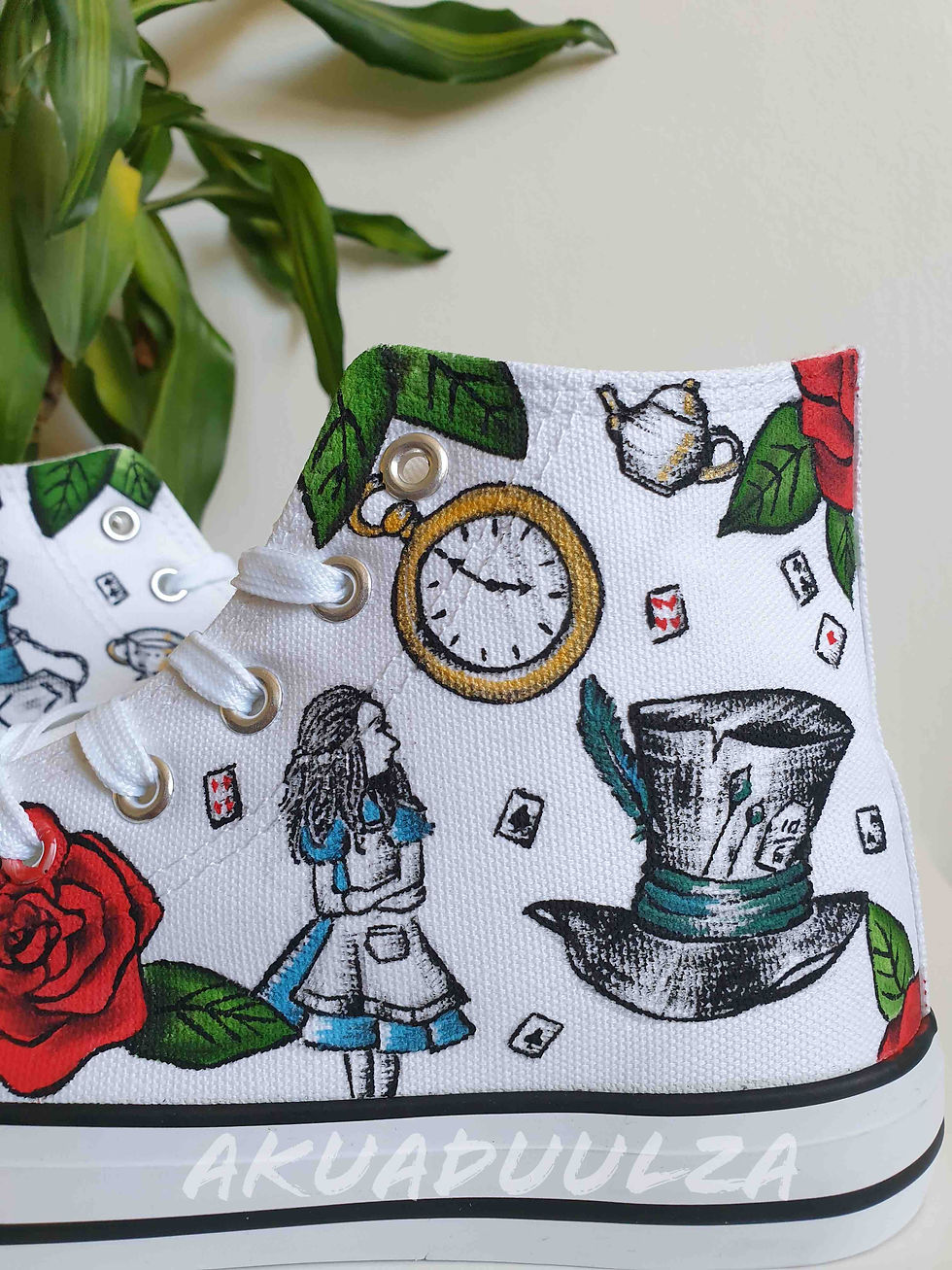 Thumbnail: Close-up of handpainted Alice in Wonderland details on white canvas shoe, intricate.