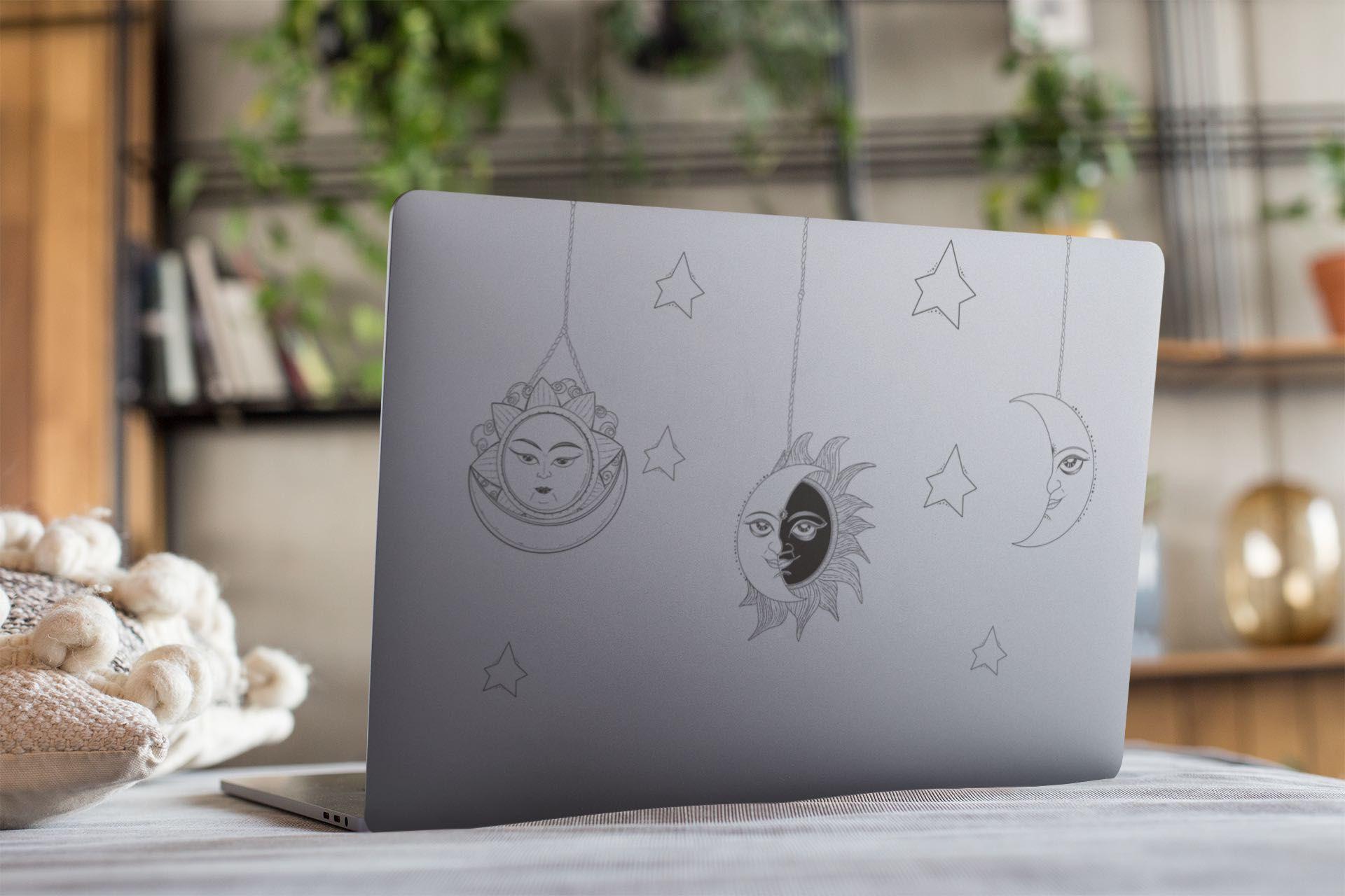 Grey laptop lid with a sun, moon, and star outline sticker .