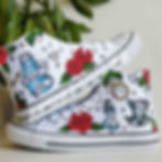 White high-top canvas shoes with handpainted Alice in Wonderland design, placed top of each other.