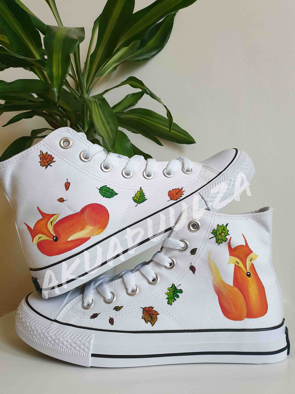 White high-top canvas shoes with handpainted fox, placed top of each other.