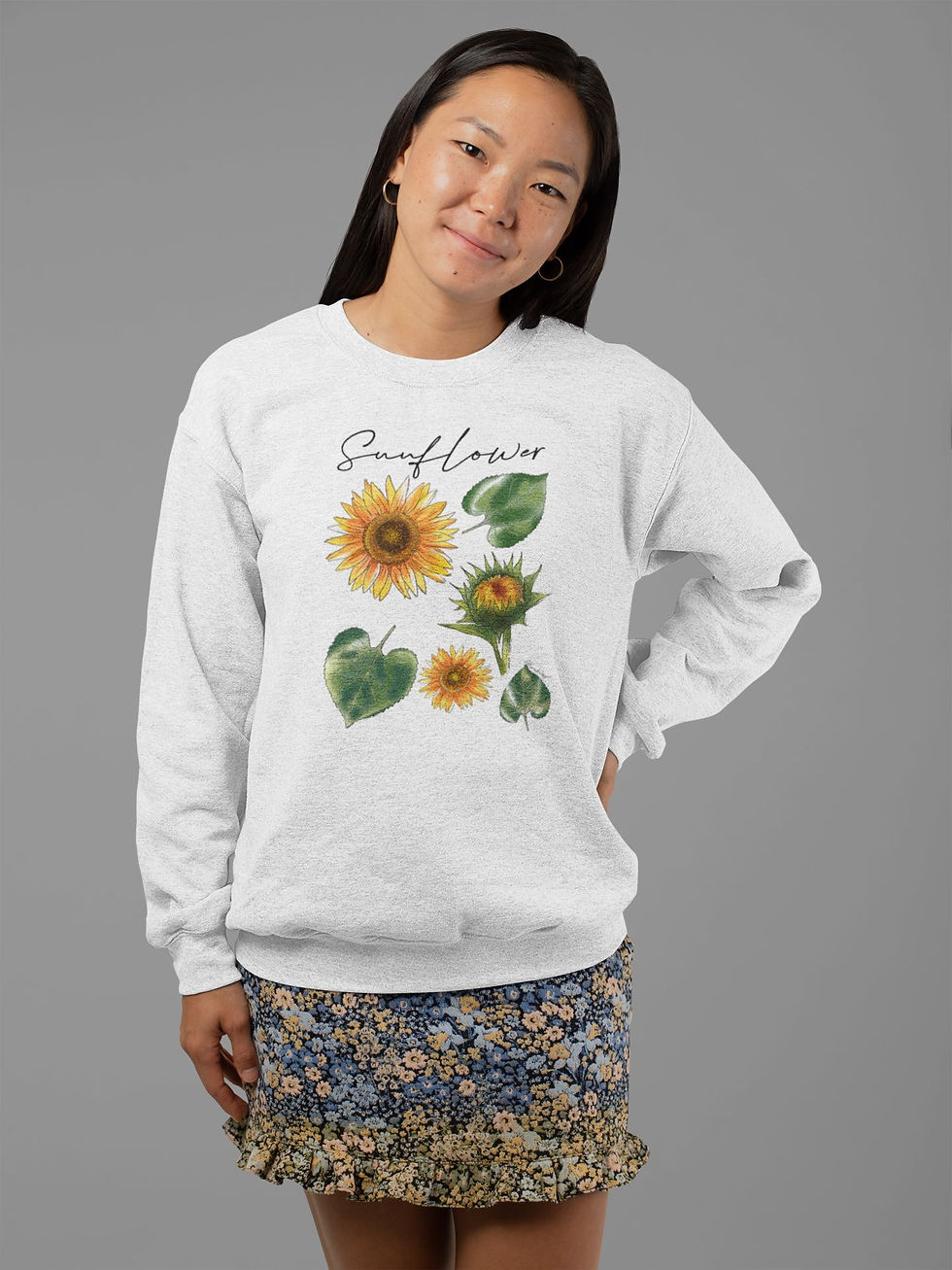 Thumbnail: A smiling woman modeling a grey sweatshirt with a sunflower graphic.