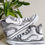 Thumbnail: Black and white hand-painted abstract design on white high-top shoes.