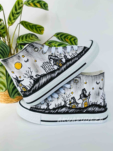 White high-top canvas shoes with handpainted spooky Halloween haunted house scene, placed top of each other.