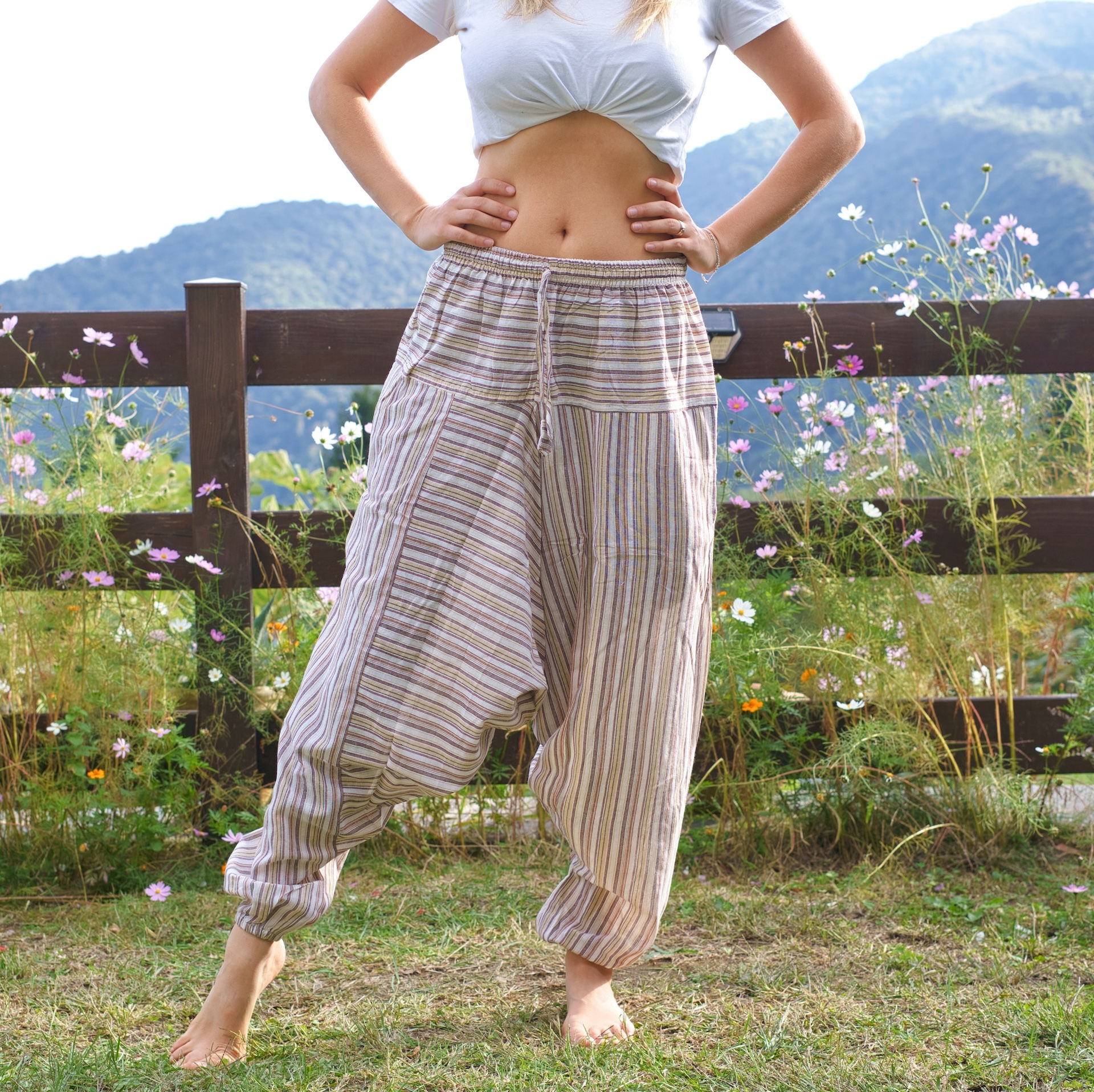 Vista frontale di persona, indossa pantaloni alla turca a righe beige.