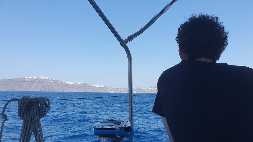 Man gazing at Santorini island and Oia city in the distance, viewed from behind, calm sea, seasickness recovery moment.