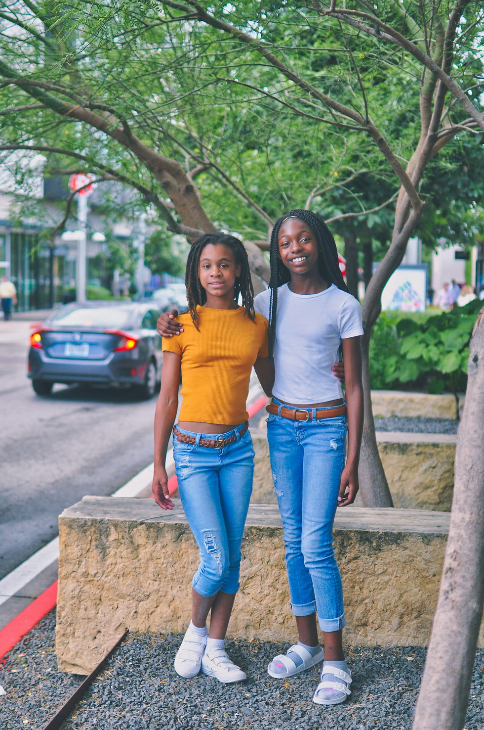 Two friends posing on a sidewalk