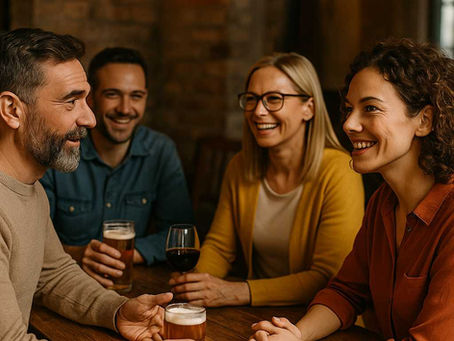Vier lächelnde Menschen sitzen in einer gemütlichen Kneipe an einem Holztisch und unterhalten sich bei Bier und Wein – entspannter Singlestammtisch in der Eifel.