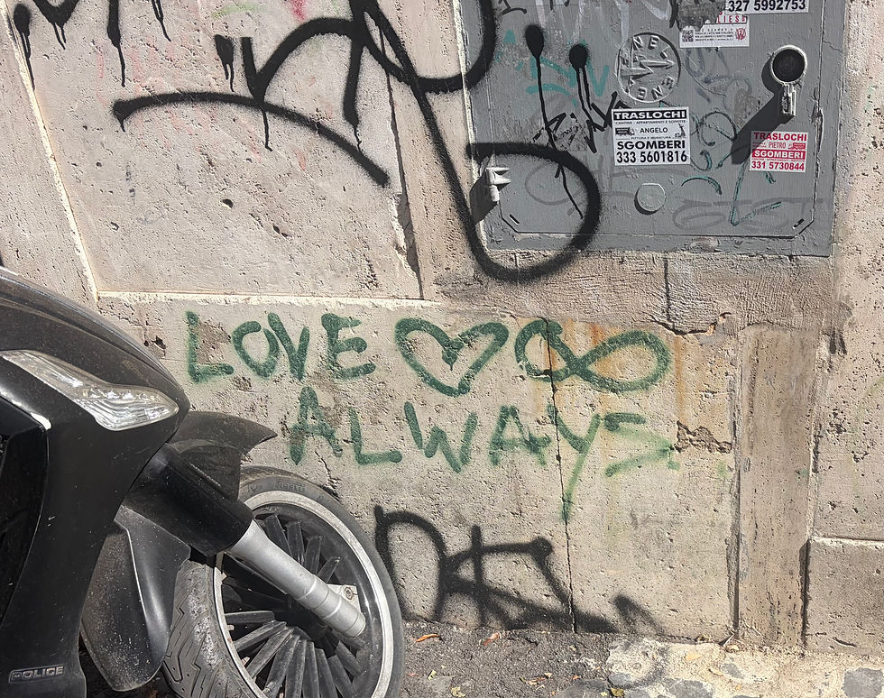 Black scooter by a graffiti-covered wall with green LOVE ALWAYS, black spray paint, and Italian removal ads on a gray panel