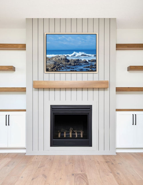 Thumbnail: Rocky shoreline with crashing waves, deep blue ocean, and birds perched on rocks under a blue sky, hung on a grey fireplace
