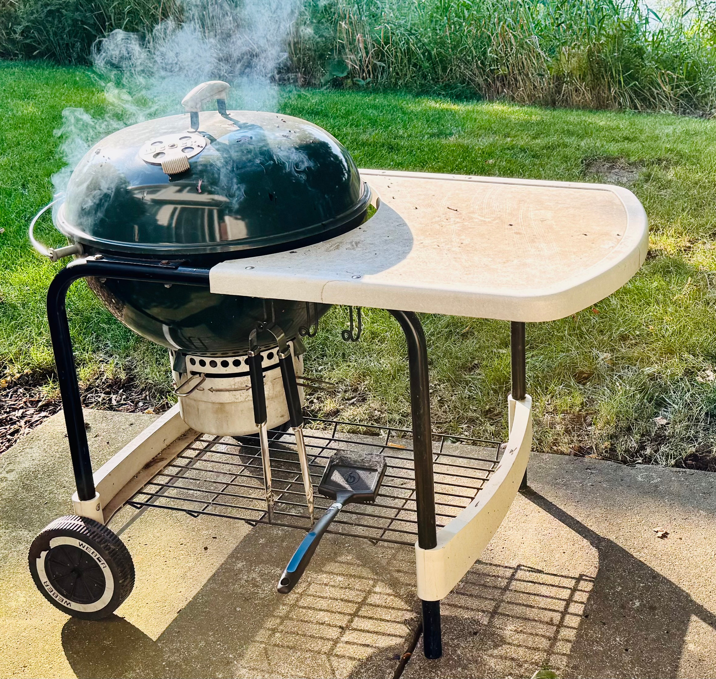 A green grill with smoke coming out of it.