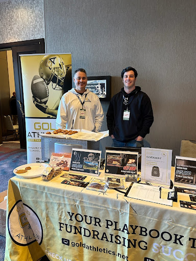 Brian Ludwig, Fundraising Coach in Pennsylvania and Colin Chatto stand behind Gold Athletics booth with Cookie Dough fundraiser samples