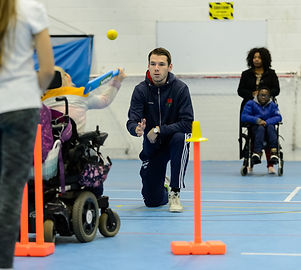 Child in wheelchair throwing a ball as part of a sports coaching session