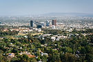 Aerial view of a city with buildings amid lush green trees.