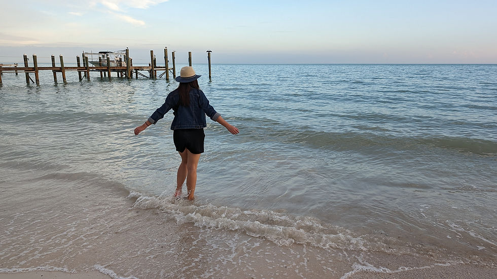 A woman standing in the ocean with her arms slightly raised