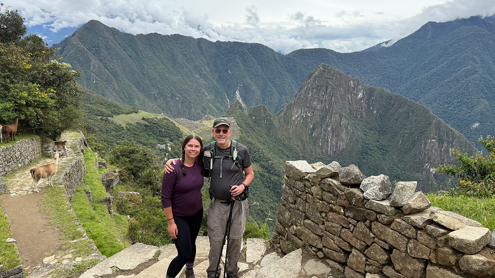A women and her father posing at the Sun Gate with Lamas and Machu Picchu in the background
