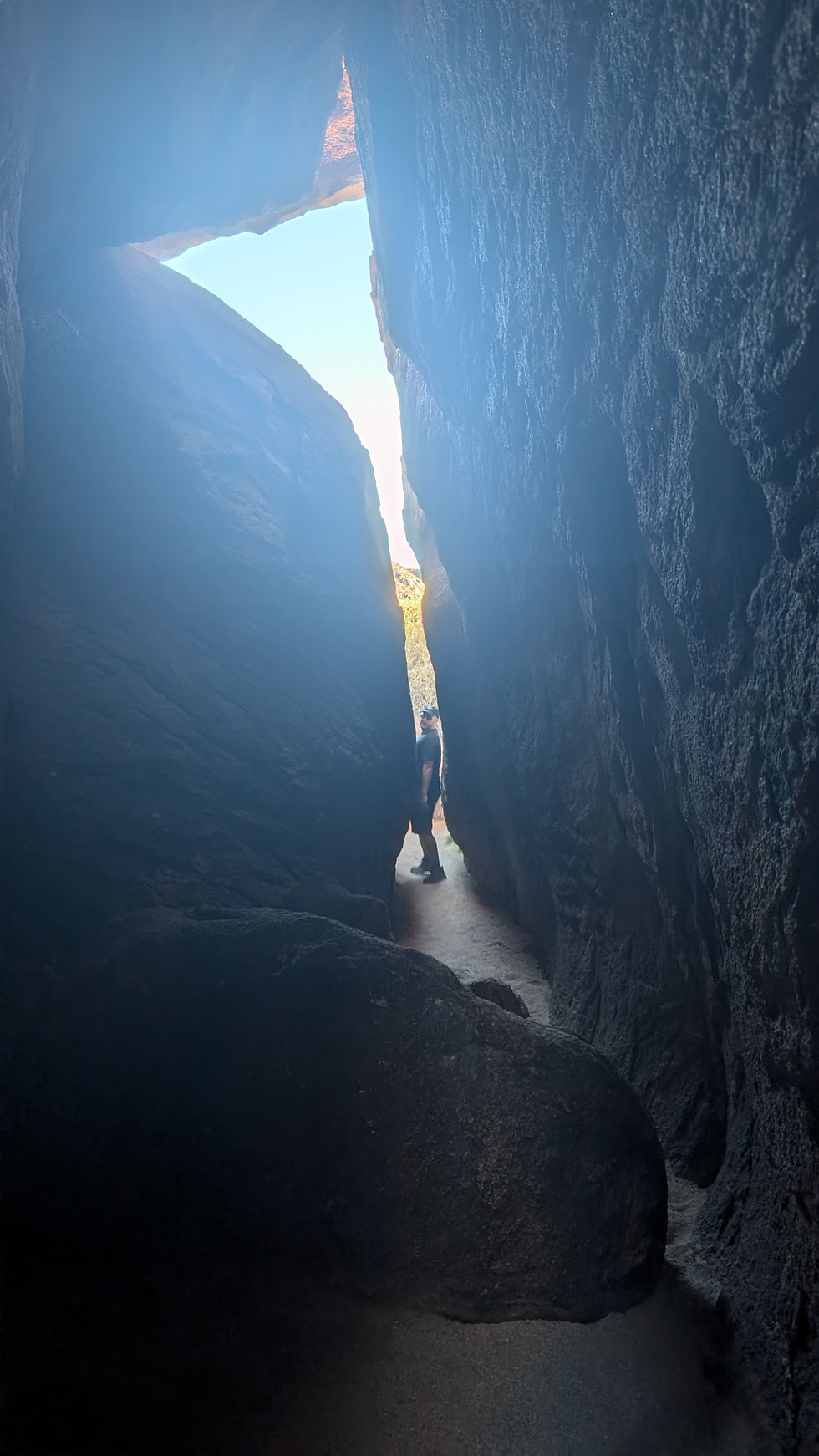 A man squeezing through a crevice in the Hall of Horrors in Joshua Tree National Park, California
